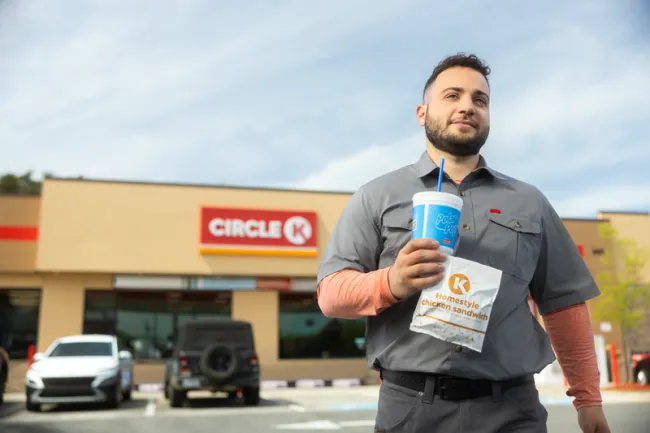 Man holding drink and food outside a Circle K station