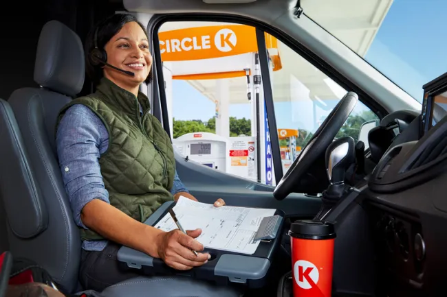 woman with headset taking a call from her van by a Circle K station