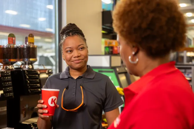 business customer talking to Circle K station employee, with drink in hand