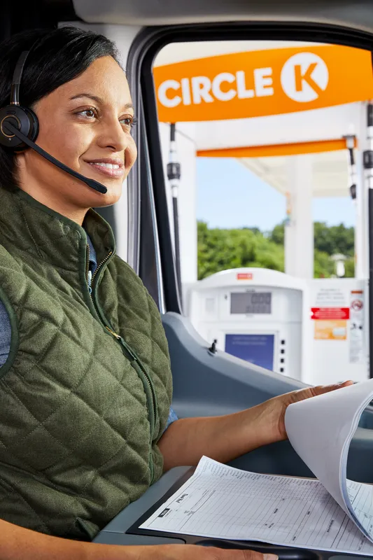 Woman sitting in a van with a headset and clipboard
