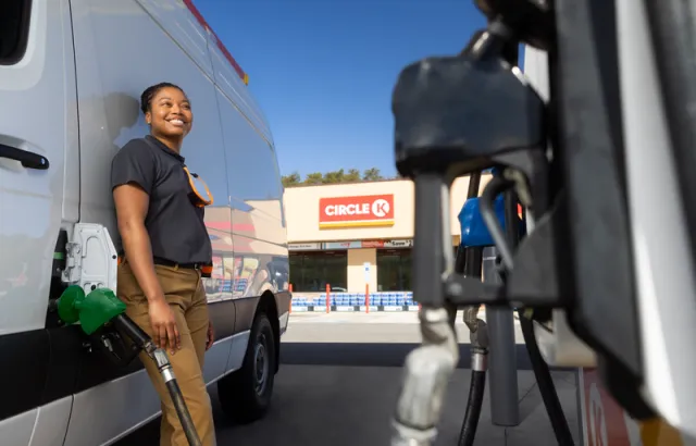 Woman leaning against her van while fueling at a Circle K station