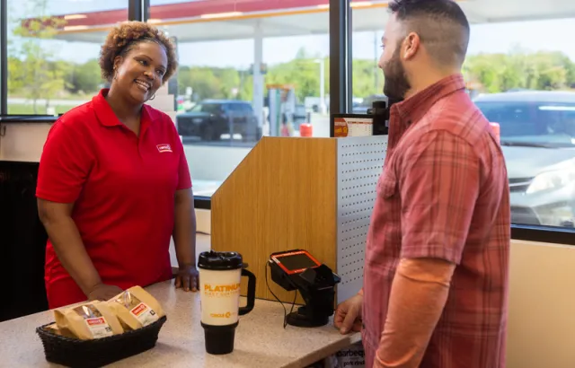 Circle K store employee talking to a business customer at the till