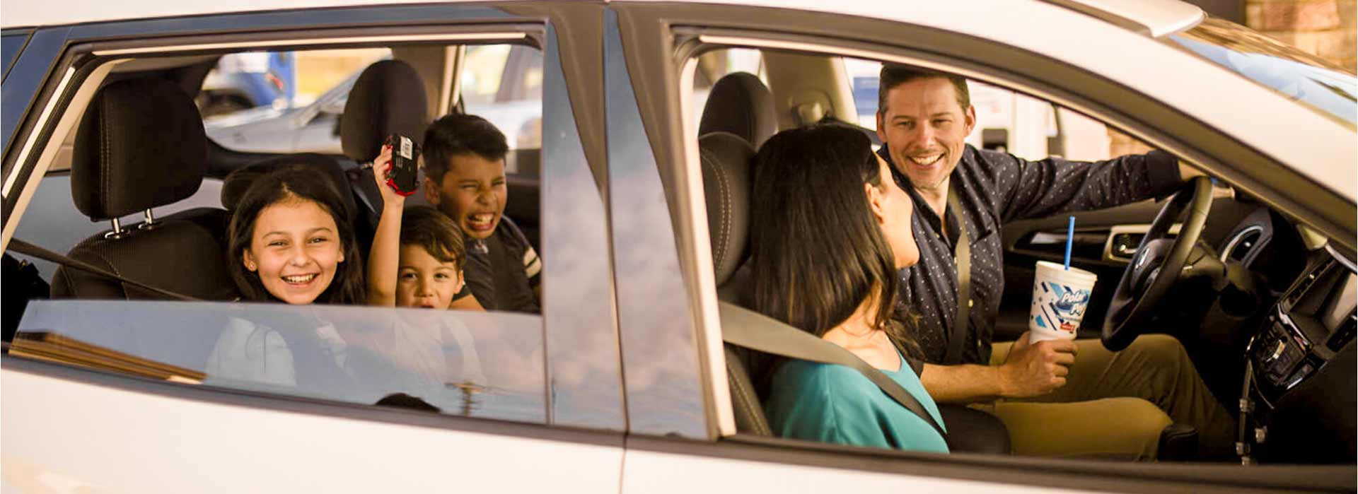 A family smiling and laughing inside their car.