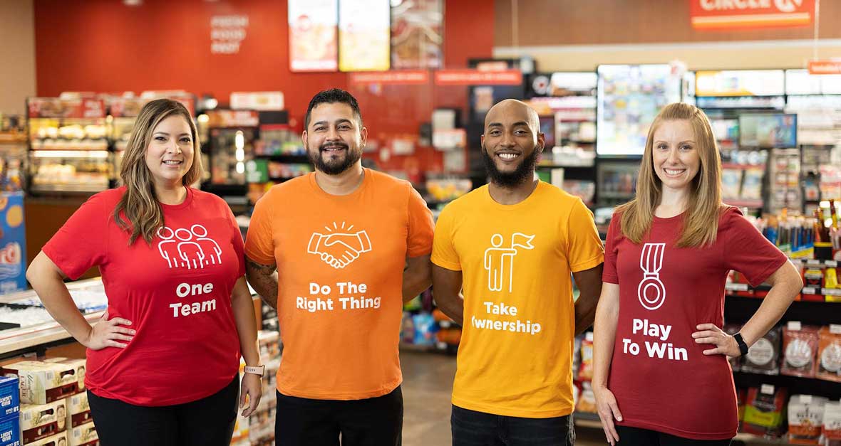 Four Circle K employees wearing t-shirts with the company's values: One team, do the right thing, take ownership, and play to win.